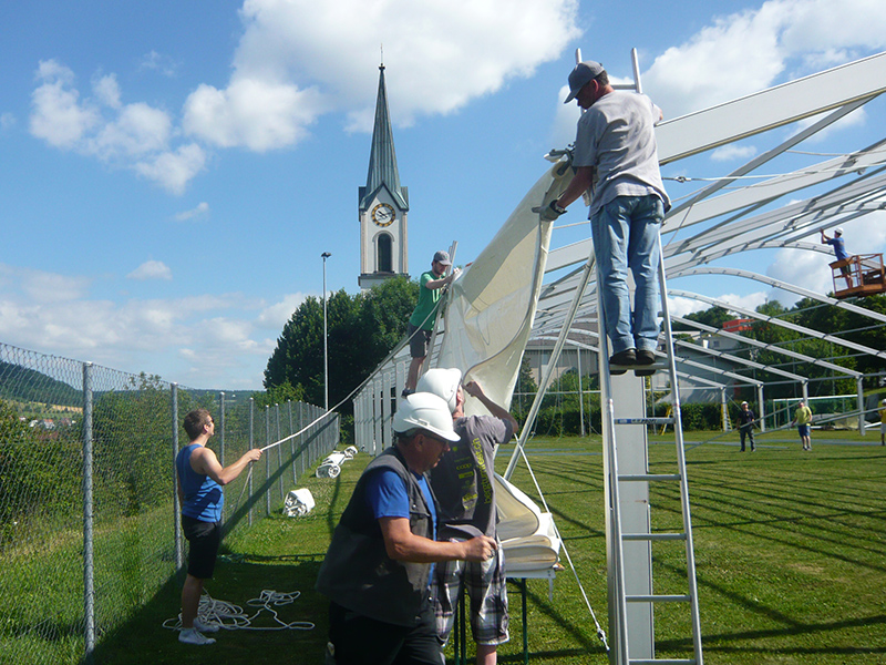 Team packt gleichzeitig mit an, um Zelt aufzubauen.